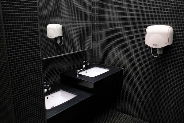 Black tiled bathroom with white sinks